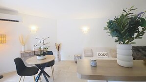 A modern dining area with a round table, black chairs, and a white vase with flowers. - Cosy garden-floor studio - Sun & beach on foot (Golfe-Juan)