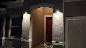 En bostadsbyggnad med en garageport, en huvudentré med dörr och två vägglampor.