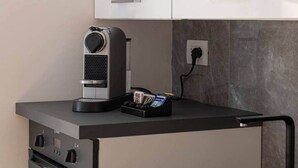 Een kitchenette met een koffieapparaat, een stopcontact en een tijdschriftenhouder op het aanrecht.