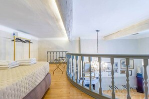 Un dormitorio con cama, balcón con barandilla y vista al interior.