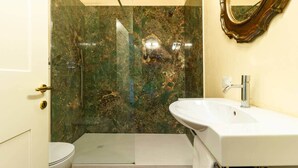 A bathroom with a marble shower wall, a white sink, and a toilet. - Casa Pegaso in Canton de Fiori (Bologna)