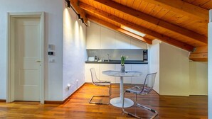 A modern kitchen with white cabinets, a round dining table, and two chairs. - Casa Pegaso in Canton de Fiori (Bologna)