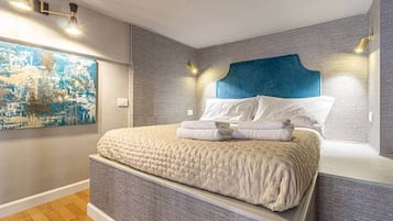 Una camera da letto moderna con un letto grande, un quadro raffigurante una vista cittadina e una particolare testiera blu.