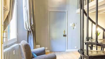 Un soggiorno moderno con un divano grigio, un termosifone, una porta e una scala.