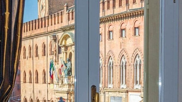Een uitzicht op een historisch gebouw met een klokkentoren en vlaggen, door een open deur.