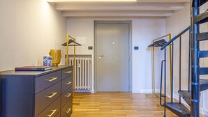 Een gang met een zwarte dressoir, een radiator en een trap met een metalen leuning.