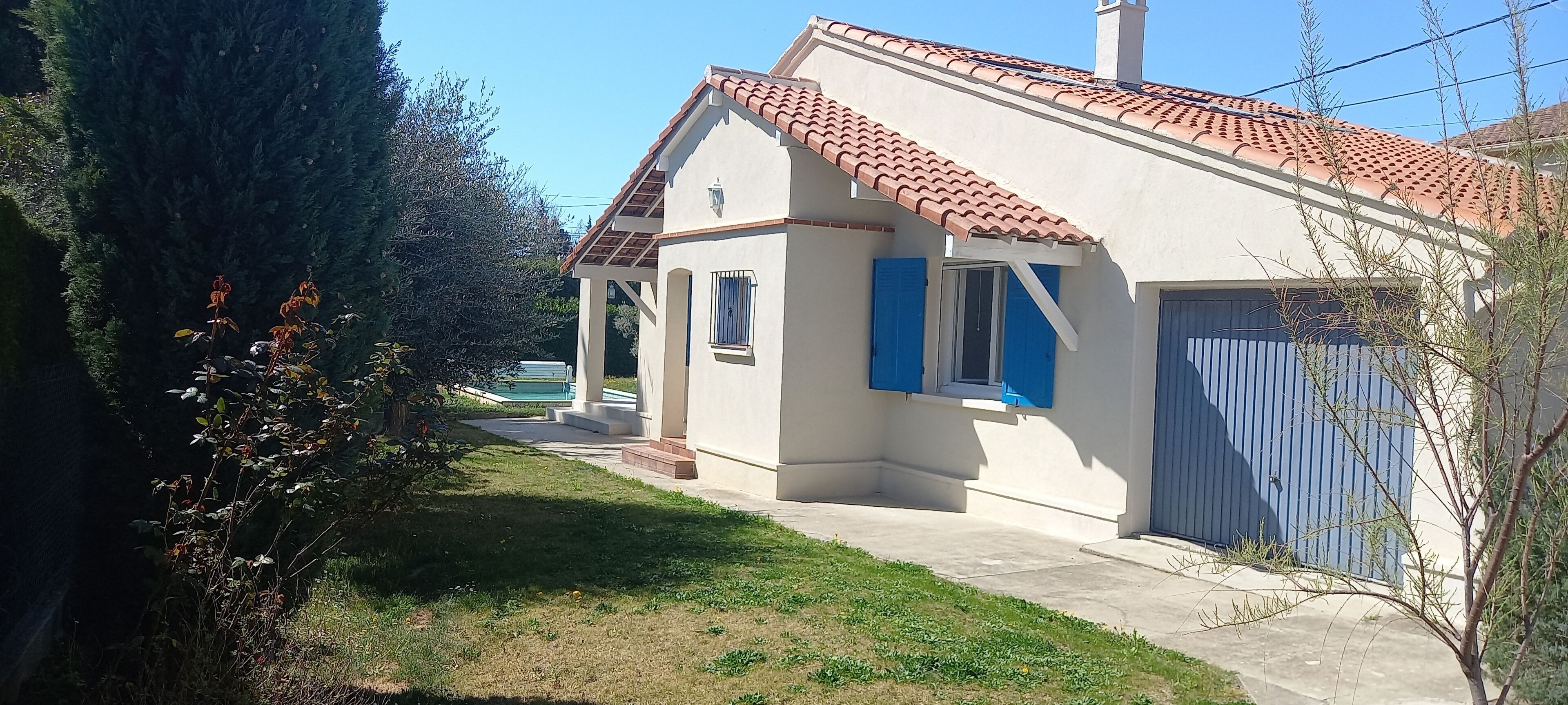 Uma casa com telhado de cerâmica, varanda coberta e garagem com porta azul.