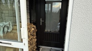 Eine schwarze Tür mit Glasfenster, ein weißer Türrahmen und eine Rampe zum Eingang.