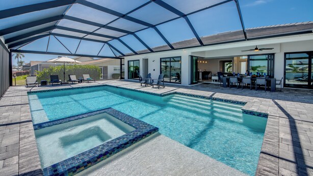 Une piscine dotée d’un toit en verre, de chaises longues et d’un espace patio.