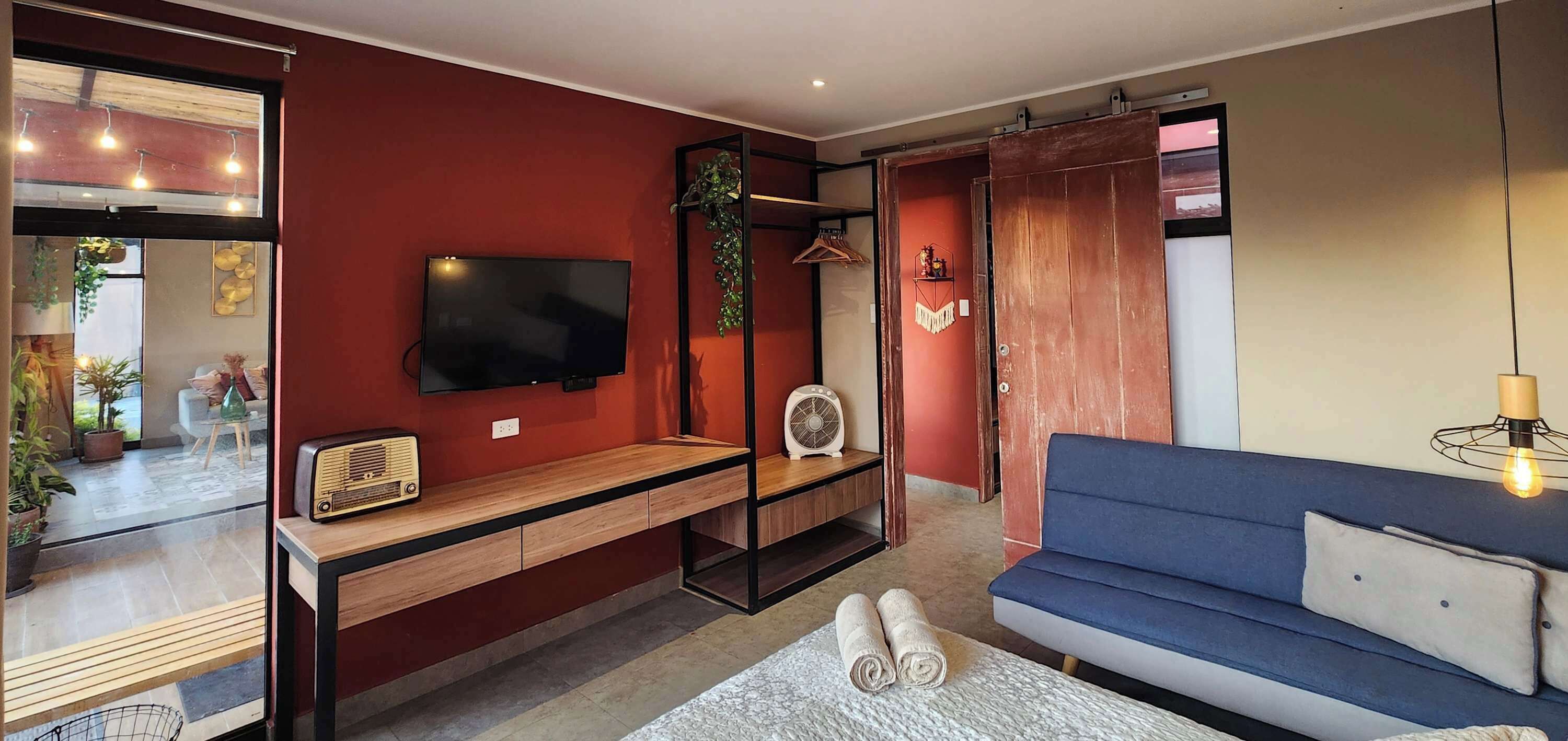 A modern living room with a TV, wooden console, blue sofa, and a sliding door closet.
