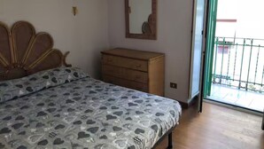 A bedroom with a bed, a wooden dresser, a mirror, and a sliding glass door to a balcony. - Celeste sea view vacation home with parking (Portici)