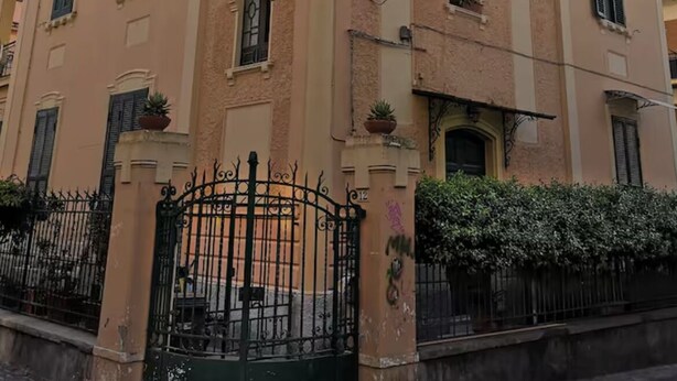 A multi-story building with a beige facade, multiple windows with shutters, and a black wrought iron gate. - Celeste sea view vacation home with parking (Portici)