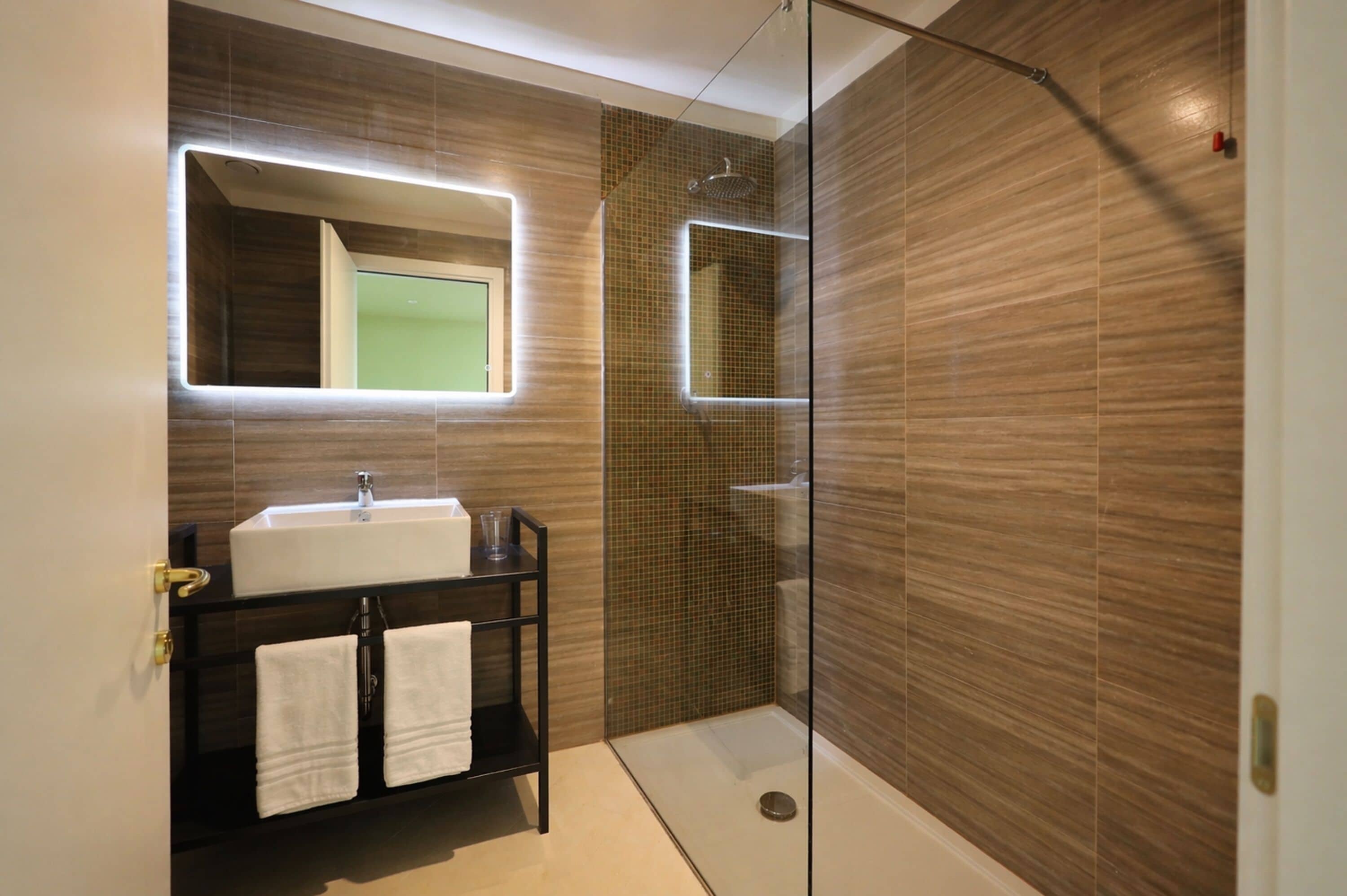 A modern bathroom with a glass-enclosed shower, a vanity with a mirror, and a sink.