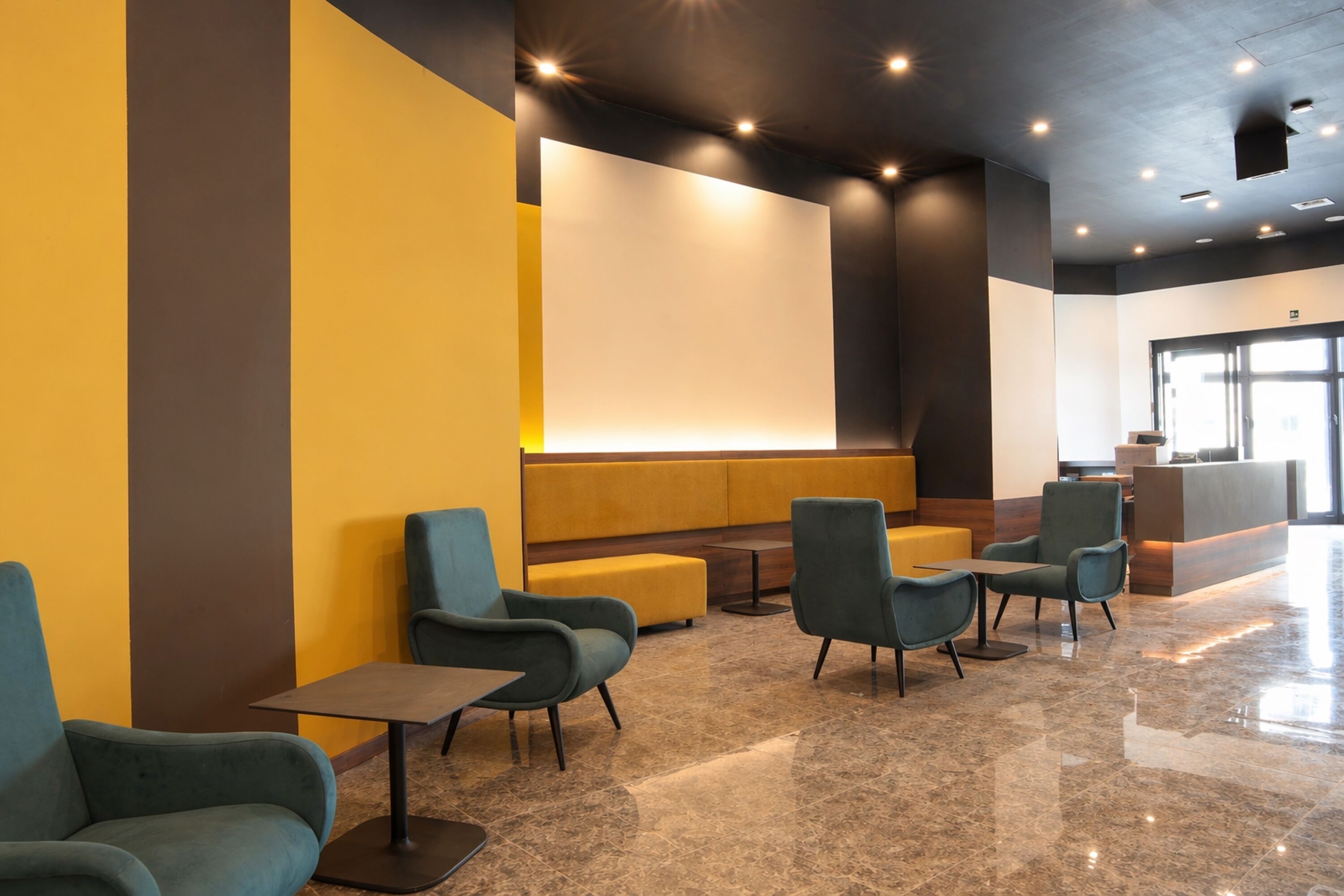 A modern lobby with seating areas, a reception desk, and a large screen.
