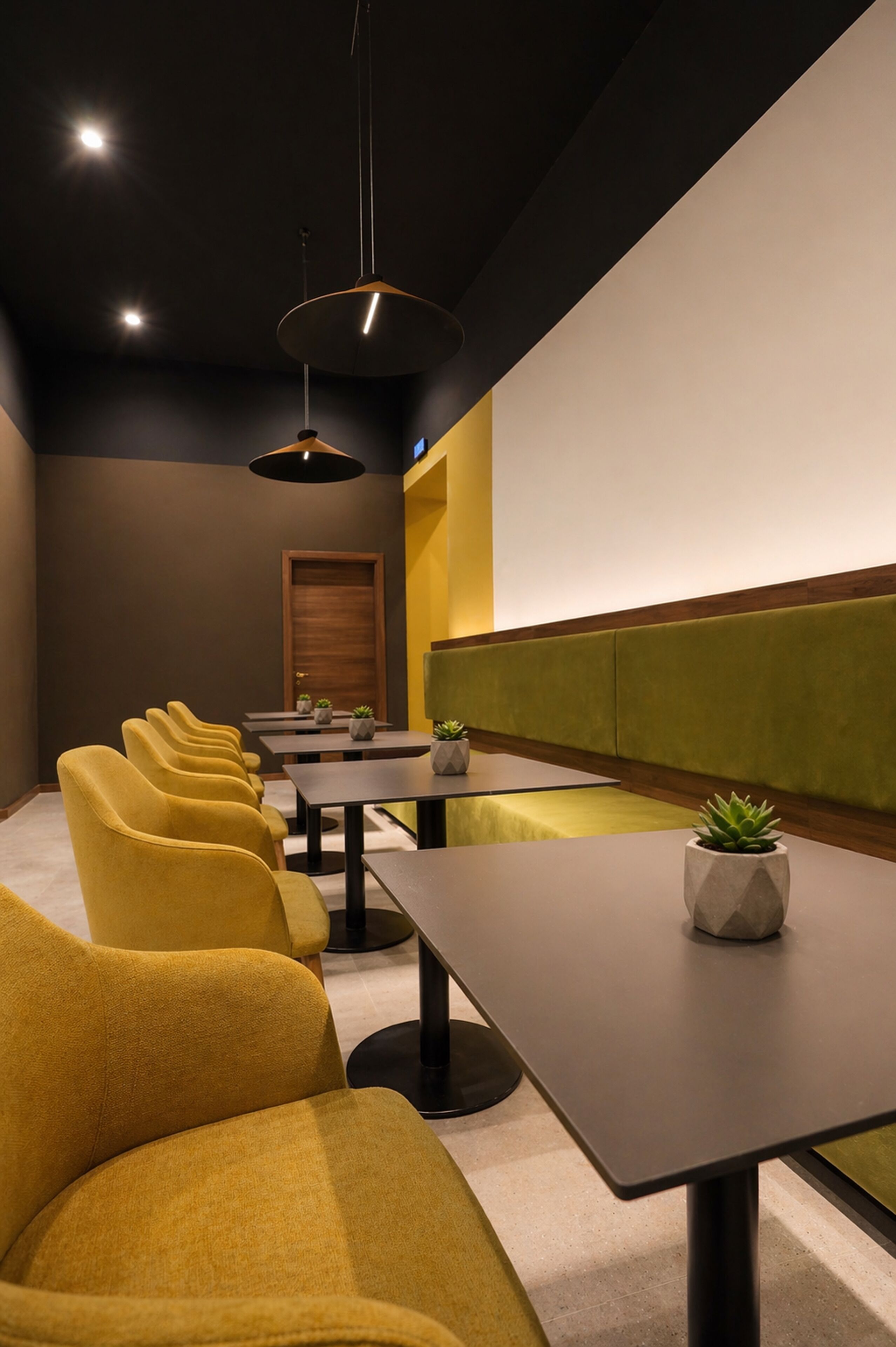 A conference room with yellow chairs, tables, and a projector screen.