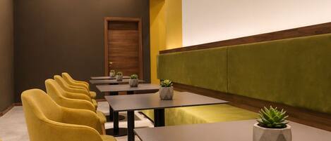 A conference room with yellow chairs, tables, and a projector screen.