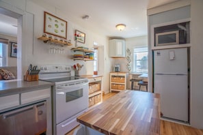 A kitchen with white appliances, wooden countertops, and a window.