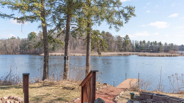 A lakeside property with a wooden deck, a stone pathway, and a view of the lake surrounded by trees. - The Blackbird Inn on Rice Lake (Rice Lake)