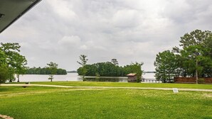 A grassy area with a lake, a small building, and trees. - Romantic 2BR on Cross Lake Boat Slip, Pier & RV Parking, family friendly (Shreveport)
