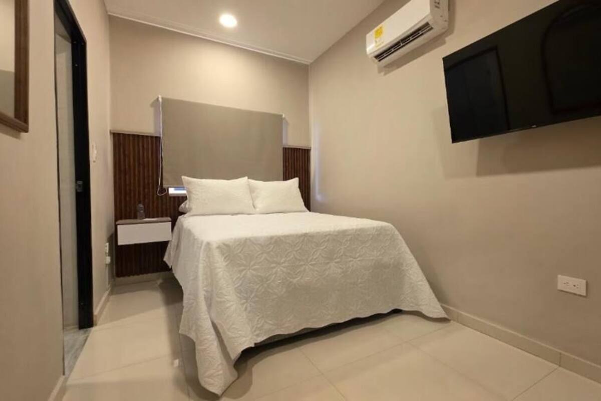 Een hotelkamer met een bed, een wandtelevisie en een airconditioning.
