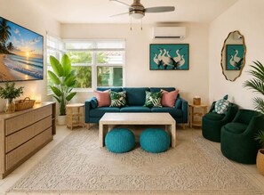 A living room with a teal sofa, a coffee table, a large plant, and artwork on the walls. - The Emerald Palms Tropical Beach Villa (Hollywood)