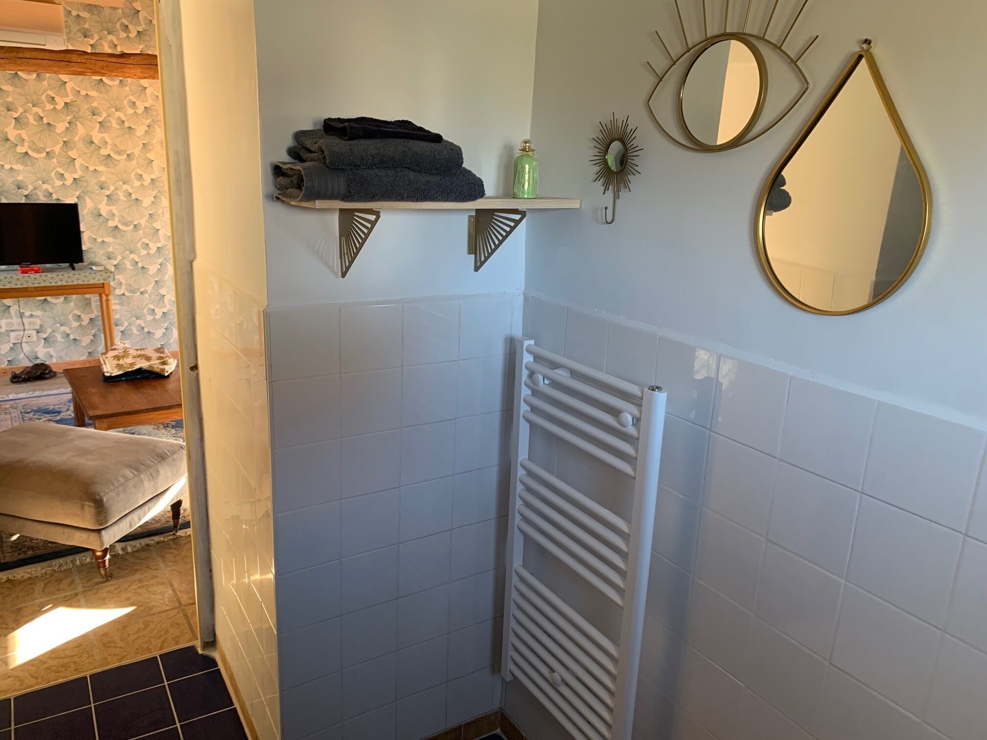 Ein Badezimmer mit weißem Heizkörper, Handtuchhalter und dekorativen Spiegeln.