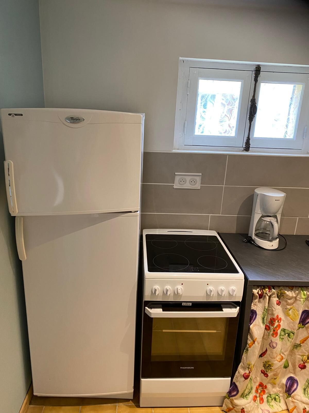 Une cuisine de taille réduite, avec un réfrigérateur blanc, une cuisinière et une machine à café.
