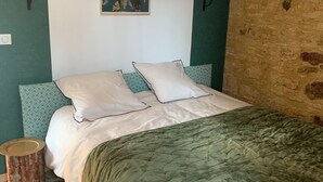 Un letto con una coperta verde, due cuscini e una testiera decorata.