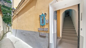 A narrow street with a building featuring a staircase leading to an entrance. - Barbera House (Positano)