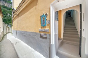 A narrow street with a building featuring a staircase leading to an entrance. - Barbera House (Positano)