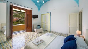 A bedroom with a bed, a chair, a TV, and a view of the outside. - Barbera House (Positano)