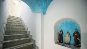 A staircase leading to a room with a blue ceiling and a niche with religious statues. - Barbera House (Positano)
