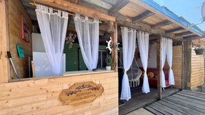 Una baita di legno con un cartello di legno, tende bianche e un piccolo portico.