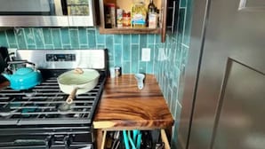 A compact kitchen with a stove, microwave, and wooden countertop.