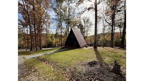 A cabin in a forested area with a grassy path leading to it.