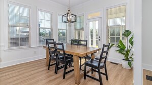 A dining area with a wooden table, black chairs, and a hanging light fixture. - Masters Week Stay in Bartram Trail Golf Community! (Evans)