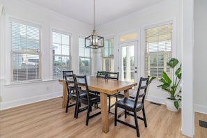 A dining area with a wooden table, black chairs, and a hanging light fixture. - Masters Week Stay in Bartram Trail Golf Community! (Evans)