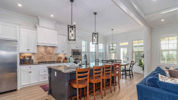 A spacious kitchen with white cabinets, a central island with bar stools, and pendant lighting. - Masters Week Stay in Bartram Trail Golf Community! (Evans)