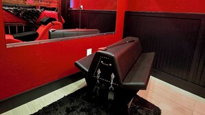 Una habitación con una pared roja, un felpudo negro, un banco, un letrero de neón y un cuadro enmarcado.