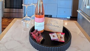 Una cocina moderna con electrodomésticos de acero inoxidable, una botella de vino y una bandeja con aperitivos.