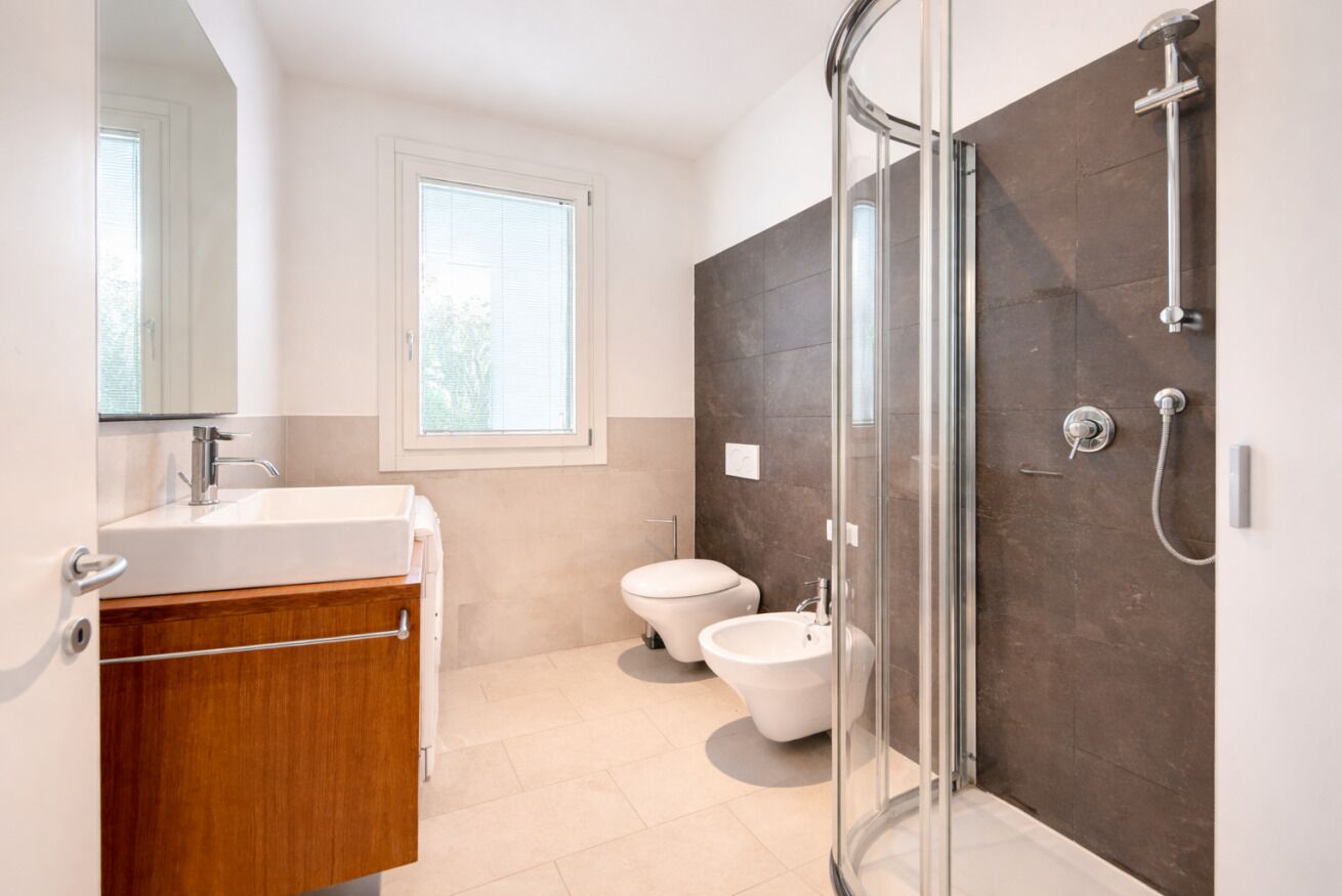 Une salle de bain moderne avec une douche à parois de verre, un lavabo, des toilettes et un bidet.