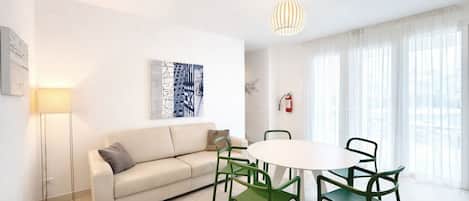 A modern living room with a sofa, a round table, and green chairs.