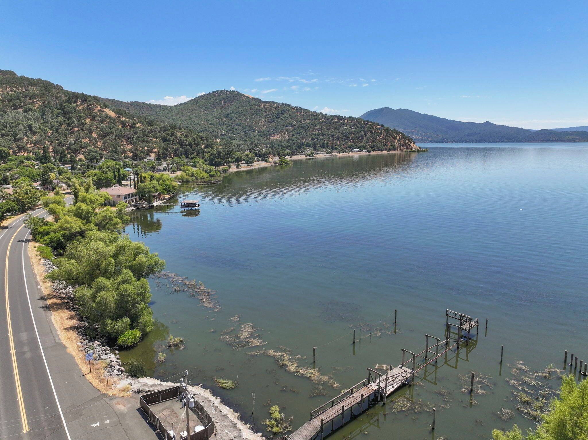 A lake with a dock and a road curving along the shore.