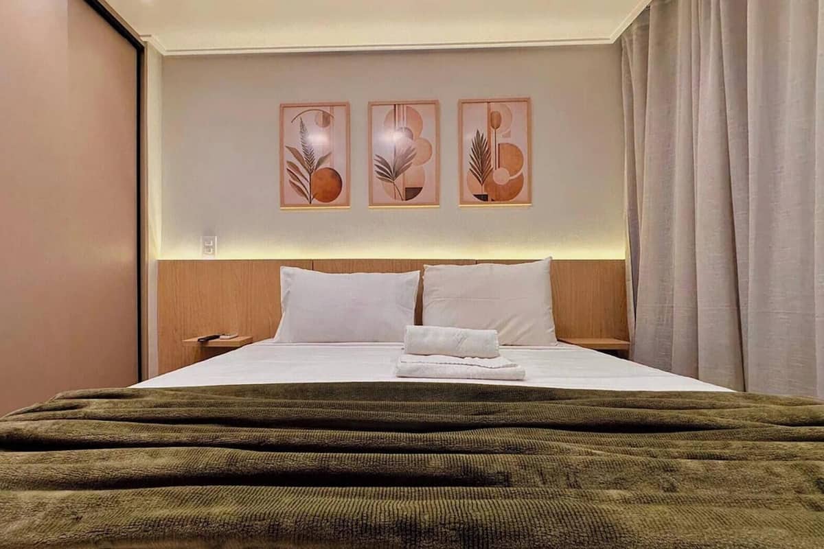 Una habitación de hotel con cama, almohadas, una colcha y decoración en la pared.
