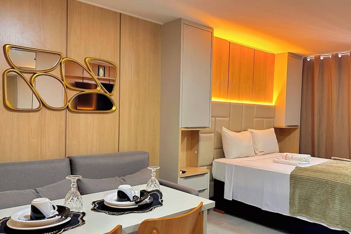 Una habitación de hotel moderna con cama, mesita de noche y un área de estar con mesa y sillas.