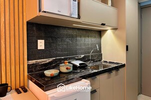 Cozinha moderna com painel de parede preto, eletrodomésticos de aço inoxidável e forno embutido.