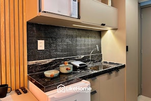 A modern kitchen with a black backsplash, stainless steel appliances, and a built-in oven. - Hit Cabo Branco III - LikeHome (João Pessoa)