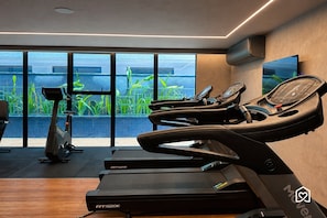 Un gimnasio moderno con cintas de correr, una bicicleta estática y una pantalla de televisión.