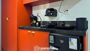Uma cozinha compacta equipada com geladeira, cafeteira e tomada.