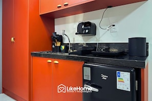 Cocina compacta con refrigerador, cafetera y toma de corriente.